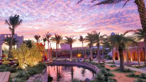 a pool in a resort with palm trees and a sunset at The Silkroad Mũi Né in Ấp Khánh Phước (1)