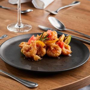 a black plate with shrimp and vegetables on a table at Hilton DoubleTree Bogotá Salitre AR in Bogotá +83 photos