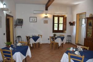 una sala da pranzo con 2 tavoli, sedie e TV di Azienda Agrituristica Biologica Il Querceto a Santa Severina