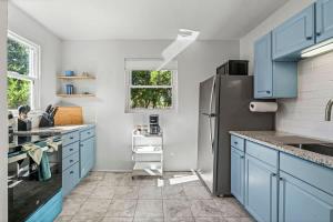 a kitchen with blue cabinets and a refrigerator at Belote Place Bungalow in Jacksonville +32 photos