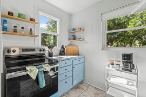 a kitchen with a stove and two windows at Belote Place Bungalow in Jacksonville