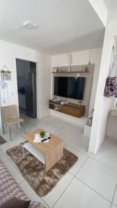a living room with a table and a large screen tv at Casa Condomínio Reserva do Delta in Parnaíba