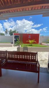 a wooden bench in front of a red building at Casa Condomínio Reserva do Delta in Parnaíba