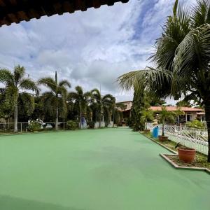 a large green tennis court with palm trees on it at Village Park Hotel in Pires Ferreira