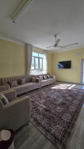 a living room with a large couch and a rug at Rosa mountain reast in Al ‘Aqar