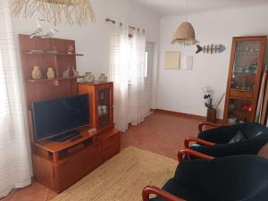a living room with a tv on a wooden entertainment center at Cantinho da Xica in Lagos
