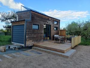 a tiny house with a deck and a table at La Tiny des Prés in LʼAbsie