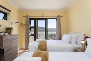 a bedroom with two beds and a balcony at Stunning Ocean & Mountain View Apartment in Glencairn