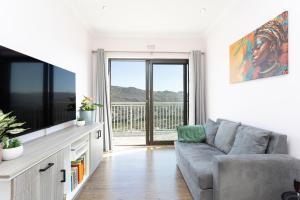 a living room with a couch and a flat screen tv at Stunning Ocean & Mountain View Apartment in Glencairn