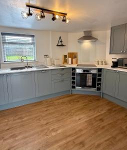 a kitchen with gray cabinets and a wooden floor at George Cottage, Alcester in Alcester