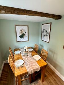 a wooden table with chairs and plates on it at George Cottage, Alcester in Alcester