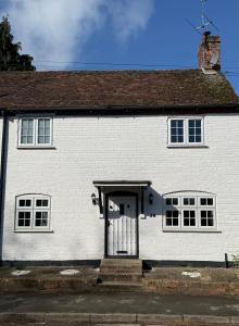 a white house with a gate in front of it at George Cottage, Alcester in Alcester