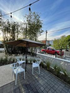 a patio with two white chairs and an umbrella at Jazz & Stay in Guadalajara