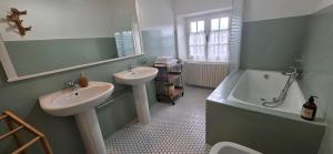 a bathroom with two sinks and a bath tub and a mirror at L'Oustal des Rameaux in Brissac