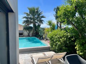 a swimming pool with two lawn chairs and palm trees at Villa Des Romieux in Pinet