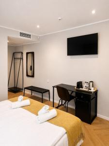 two beds in a room with a desk and a flat screen tv at NOVO Studio Hotel in Râmnicu Vâlcea