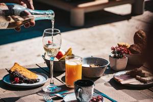 a person pouring a glass of wine on a table with food at HOTEL VILLE LA PLAGE & BEACH CLUB in Búzios