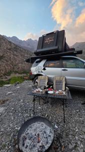 a table and chairs next to a van with a grill at car camping rental in Shkodër