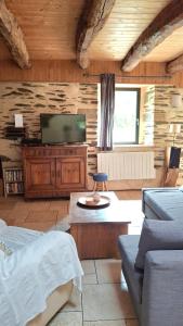 a living room with a flat screen tv and a couch at Charmante longère forestière proche Lac de Guerlédan in Sainte-Brigitte