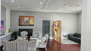 a living room with white chairs and a couch at Jacaranda Escape in Pretoria