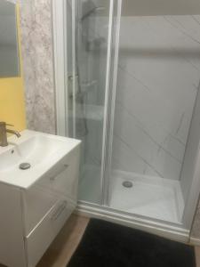 a white bathroom with a shower and a sink at Au Petit Bouchon in Le Breuil