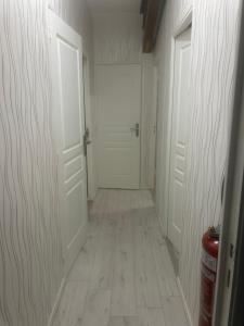 a hallway with two white doors and a tile floor at Au Petit Bouchon in Le Breuil +3 photos