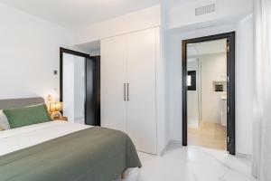 a white bedroom with a bed and a sliding glass door at Los Naranjos House in Marbella