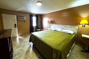 a hotel room with a bed with a green bedspread at Briarwood Motel Near Valdosta University I 75 in Valdosta