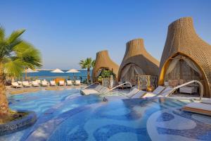 a resort with a swimming pool with chairs and umbrellas at Waldorf Astoria Doha Lusail in Doha