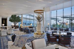 a hotel lobby with tables and chairs and a clock at Waldorf Astoria Doha Lusail in Doha