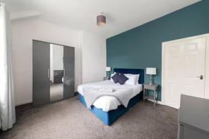 a bedroom with a bed with a blue wall at The Cosy Durham Nest in Langley Park