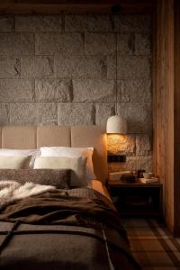 a bedroom with a bed and a stone wall at Gorczański Lux Chalet in Szlembark