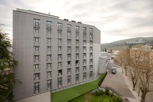 a large white building with a green lawn in front of it at Pine Astoria Hotel in Tbilisi City