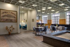 a waiting room with tables and chairs and windows at Pine Astoria Hotel in Tbilisi City