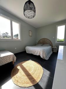 a bedroom with two beds and a rug on the floor at L'échappée Belle Maison entre Pins et Océan in Bias