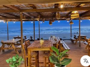 a wooden deck with tables and chairs on the beach at L'échappée Belle Maison entre Pins et Océan in Bias