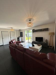 a living room with a couch and a television at L'échappée Belle Maison entre Pins et Océan in Bias