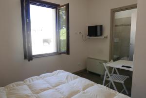 een slaapkamer met een bed, een raam en een bureau bij Agriturismo Boschi Celati in Roncaglia