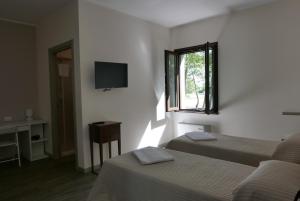 Roncaglia的住宿－Agriturismo Boschi Celati，配有电视和窗户的客房内的两张床