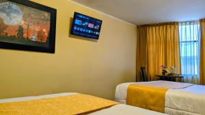a hotel room with two beds and a tv on the wall at Hotel San Lázaro Arequipa - Cochera - Hotel en Arequipa in Arequipa