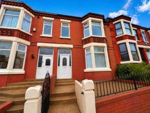 a red brick house with white doors and stairs at New Brighton Beach in Wallasey
