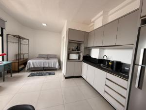 a kitchen with white cabinets and a bed in the background at Studio Smart Ponte da Amizade in Foz do Iguaçu +9 photos