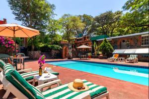 a pool with chaise lounge chairs and an umbrella at Hotel La Posada del Valle in Tepoztlán