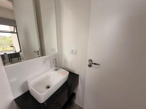 a white bathroom with a sink and a mirror at Studio Smart Ponte da Amizade in Foz do Iguaçu