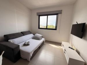 a room with two beds and a couch and a window at Studio Smart Ponte da Amizade in Foz do Iguaçu