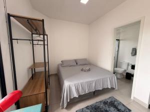 a small bedroom with a bed and a room with a toilet at Studio Smart Ponte da Amizade in Foz do Iguaçu