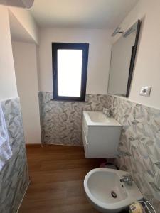 a bathroom with a toilet and a sink and a window at Ondablurooms1 in Pizzo