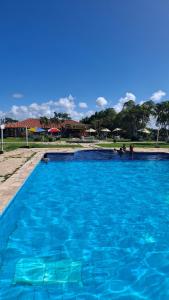 a large blue swimming pool with people in it at Chalet da Bela Vista in Itamaracá