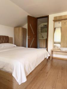 a bedroom with a large white bed and wooden floors at Pensiunea Laura in Chişcău