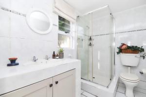 a white bathroom with a shower and a toilet at Walk Waterfront CliffPath Fireplace Secure-Parking in Hermanus +10 photos